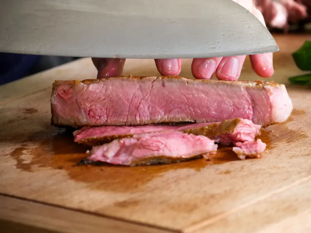 Ein saftiges Kalbskotelett sous vide wird auf einem Holzbrett in Scheiben geschnitten.