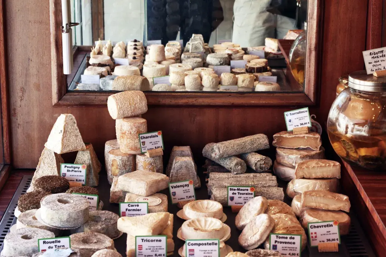 En ostdisk fylld med olika ostar, från pyramidformade till runda, med etiketter som "Charolais" och "Valençay". En stor burk med vätska står bredvid. En ost med namnet "parmesan gravid" skulle passa perfekt här.