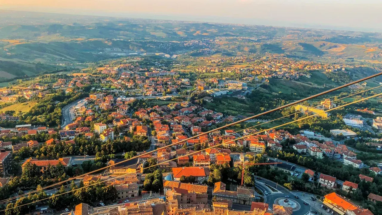 Widok na San Marino z góry, z dachami domów i zielonymi wzgórzami. Czy do San Marino potrzebny jest paszport? Nie, wystarczy dowód osobisty.
