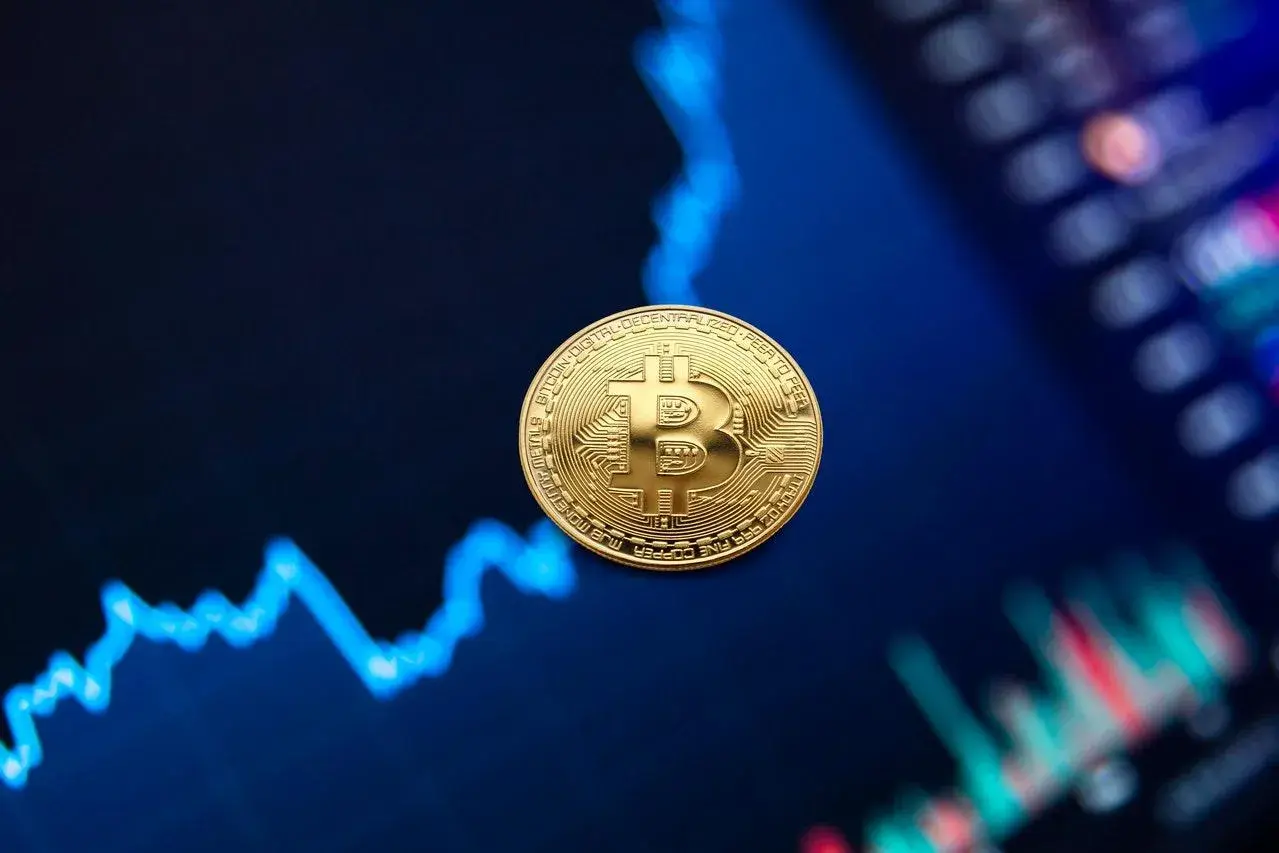 Złota moneta Bitcoin na tle wykresu finansowego.