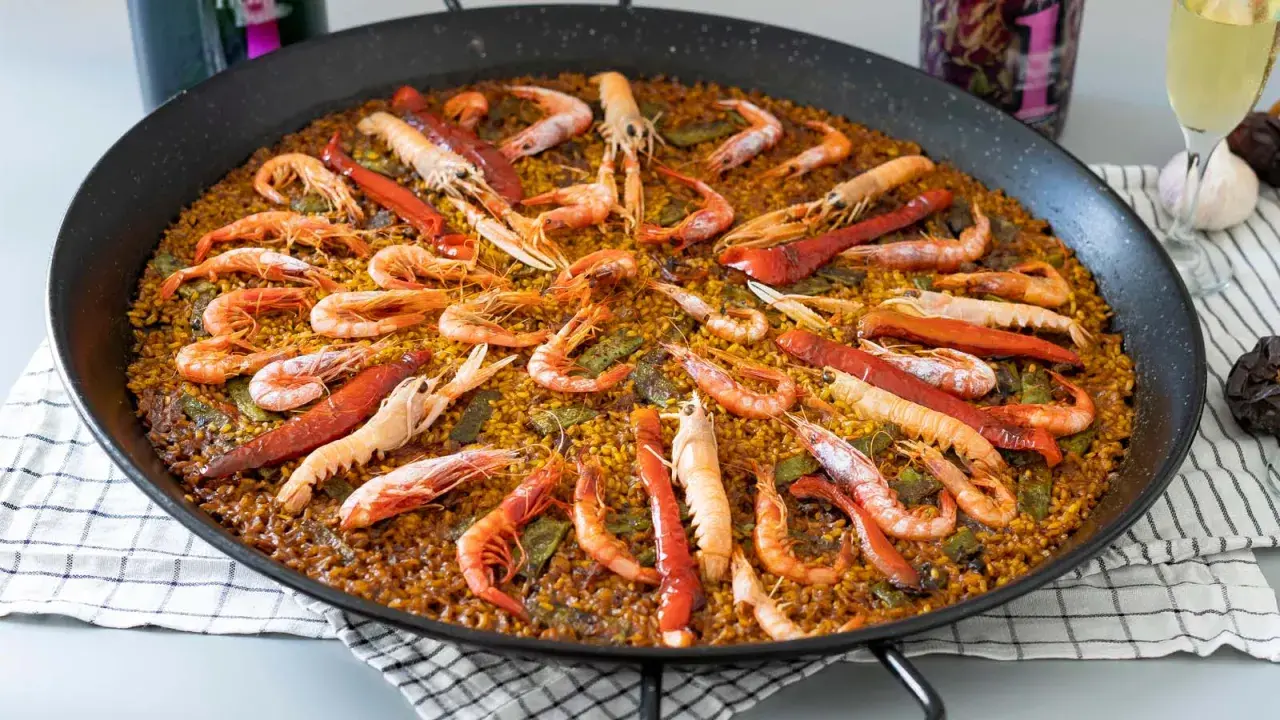 Paella gigante con gambas y pimientos rojos, perfecta para compartir. Cada porción de arroz está llena de sabor.