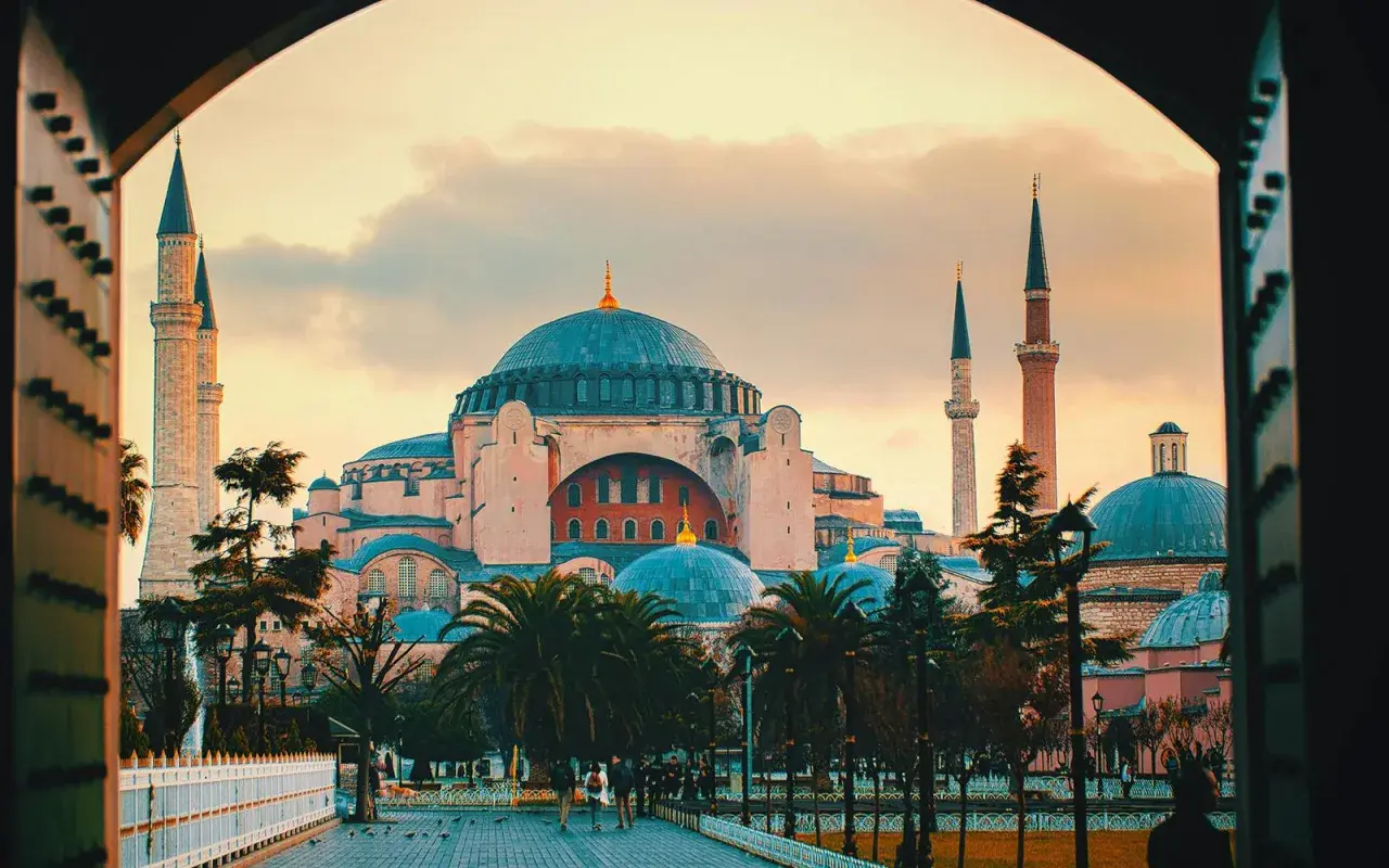 Blick durch einen Torbogen auf die Hagia Sophia mit ihren Kuppeln und Minaretten im Abendlicht. Der Eintritt in dieses historische Meisterwerk ist ein unvergessliches Erlebnis.