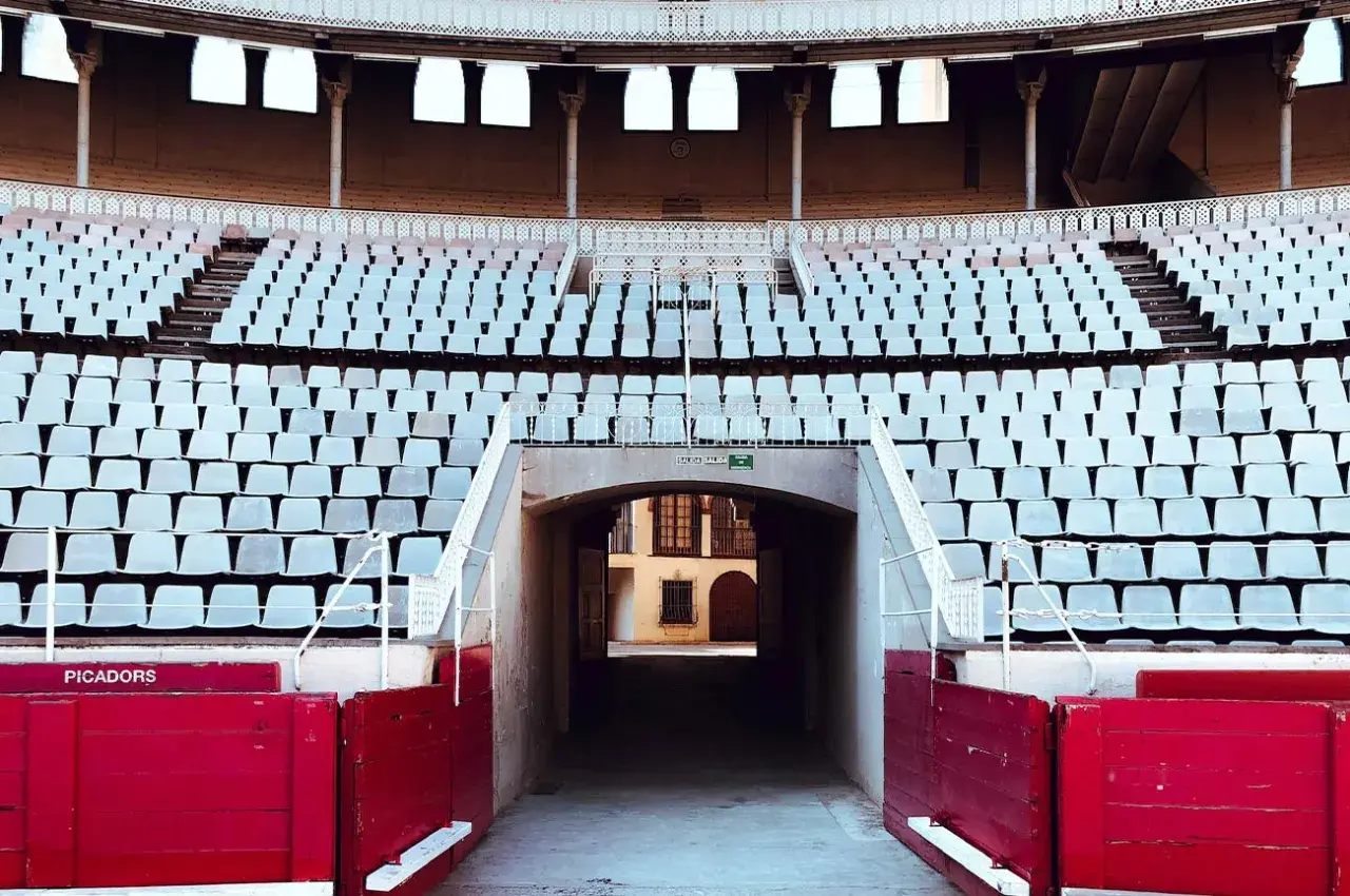 Tendidos vacíos en la plaza de toros de Las Ventas, con el plano de asientos visible y barreras rojas de picadores.