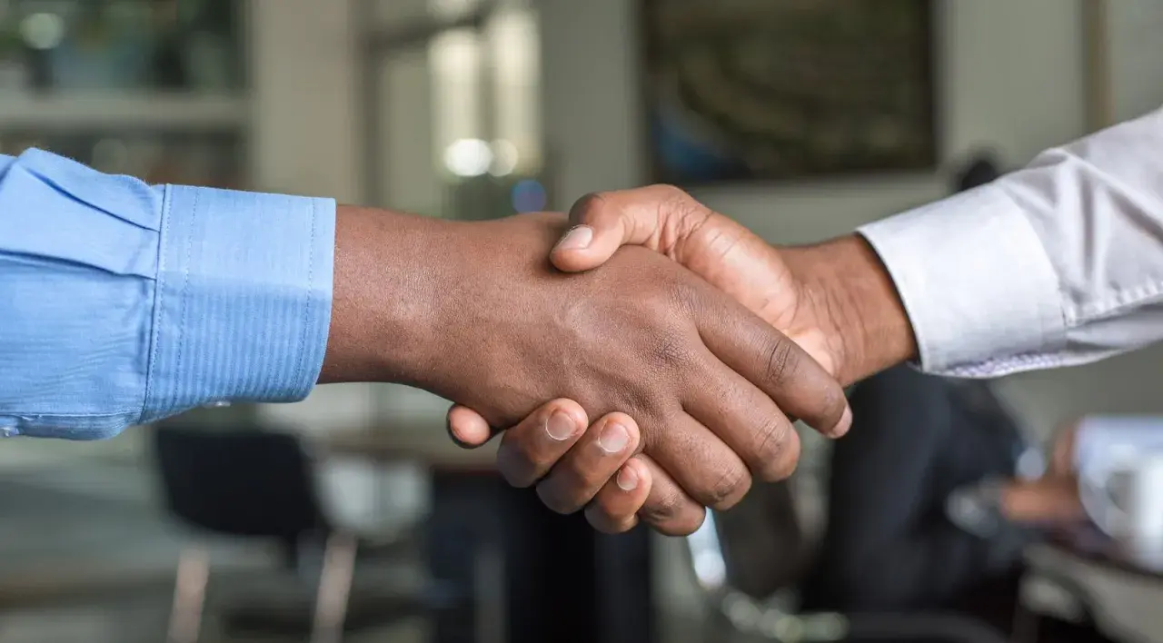 Dos hombres se dan la mano, sellando un acuerdo. Un apretón de manos que podría ser el inicio de un modelo precontrato exitoso.