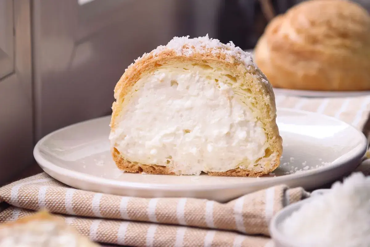 Bignè ripieno di crema soffice, cosparso di zucchero a velo che ricorda fiocchi di neve.