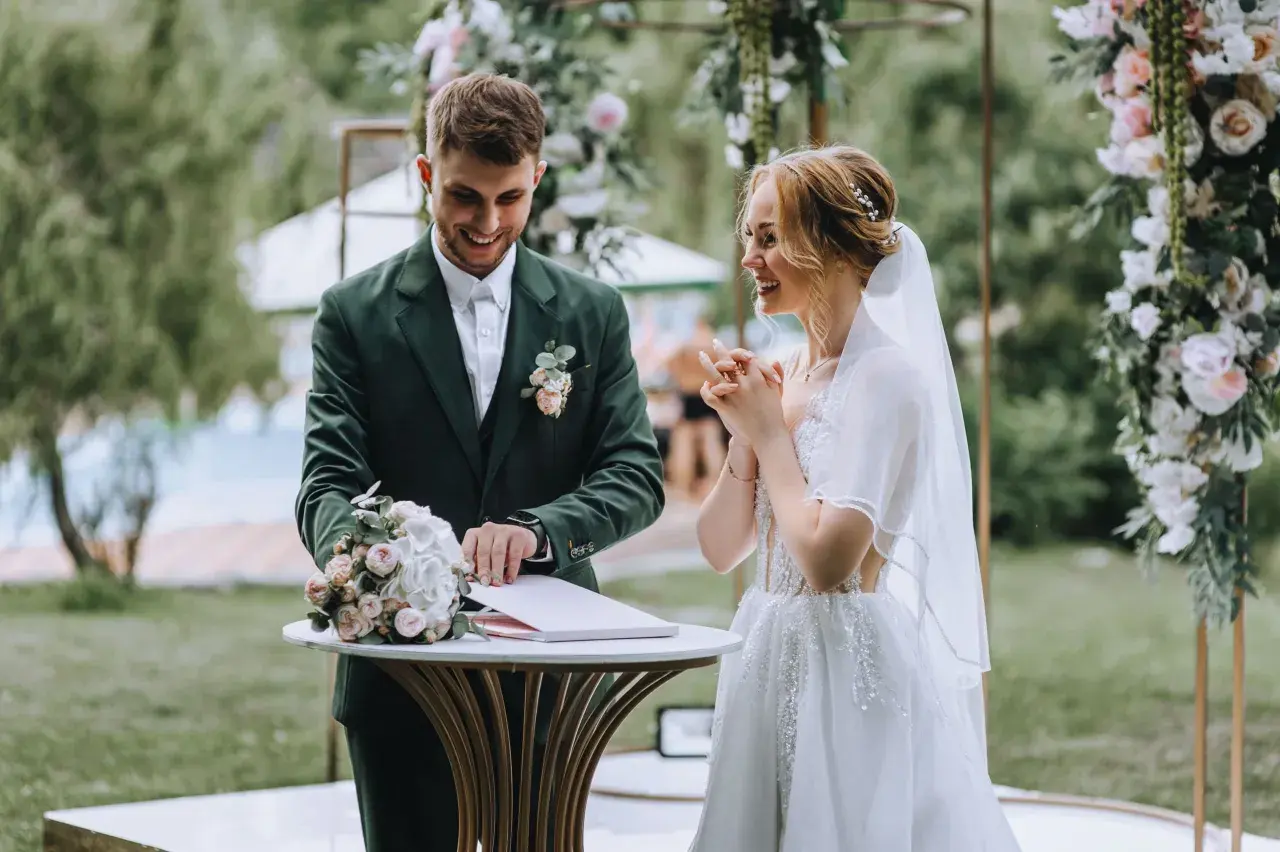 Para młoda podczas ceremonii ślubnej na tle dekoracji z kwiatów.
