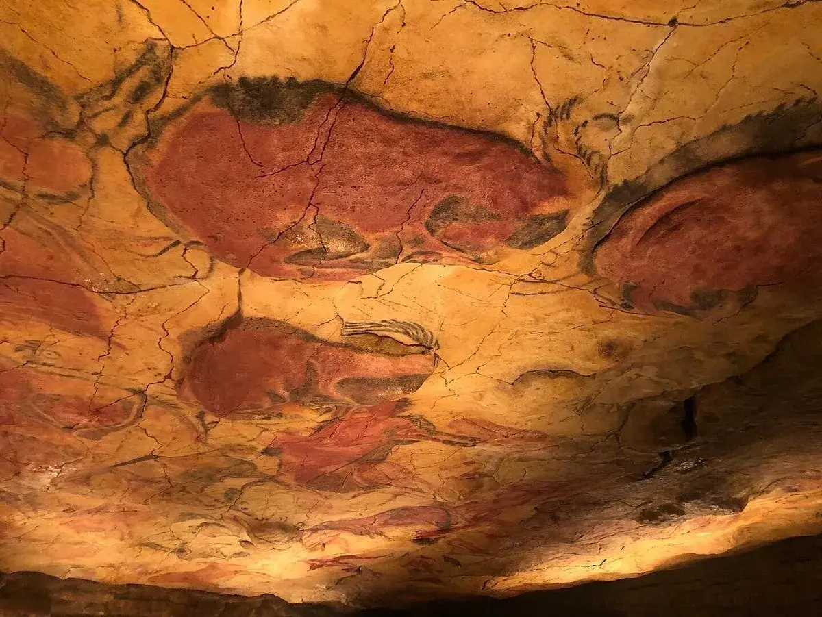 Pinturas rupestres de bisontes en el techo de una cueva, evocando el **museo mitológico Santillana del Mar**.