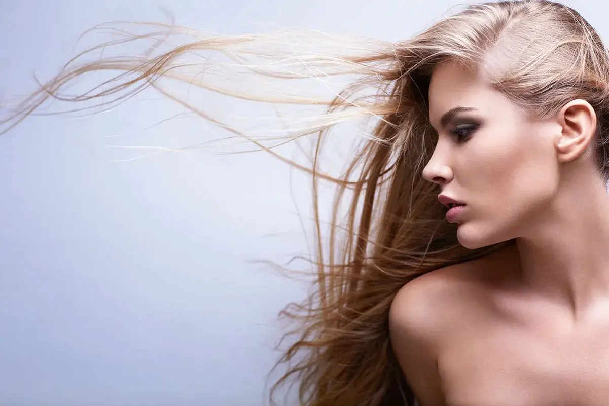 Profilo di donna con lunghi capelli biondi mossi dal vento, sguardo intenso.