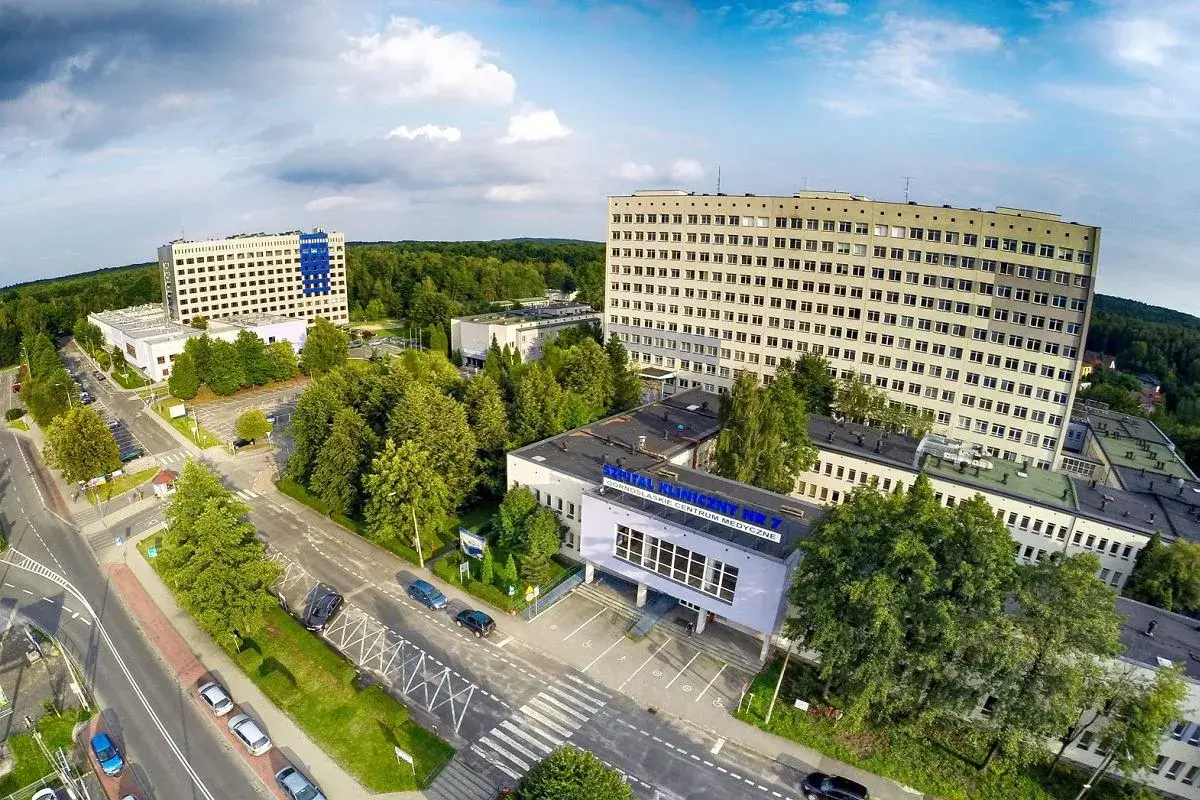 Widok z lotu ptaka na kompleks budynków szpitalnych otoczony zielenią.
