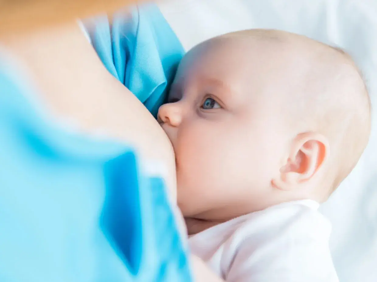 Un neonato si nutre al seno. La domanda su quanto deve mangiare un neonato è comune tra i neogenitori.