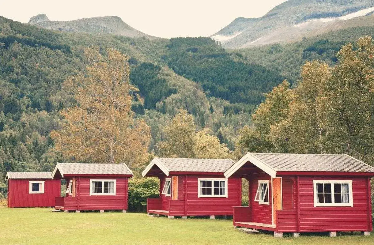 Czerwone domki kempingowe w malowniczej scenerii górskiej, idealne na camping w Norwegii.