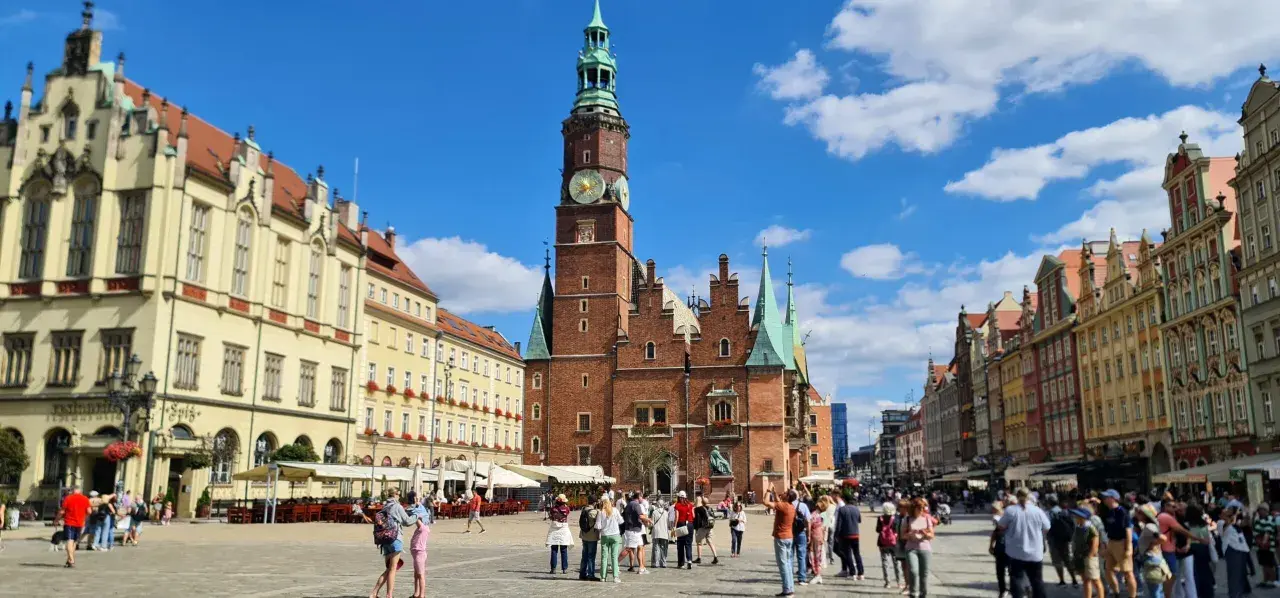 Tętniący życiem Rynek we Wrocławiu, z Ratuszem w centrum. Ludzie spacerują, podziwiając piękną starówkę wrocław.