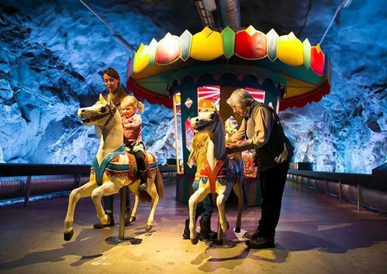 Familj njuter av en karusell i en grotta, en del av Stockholm Toy Museum.