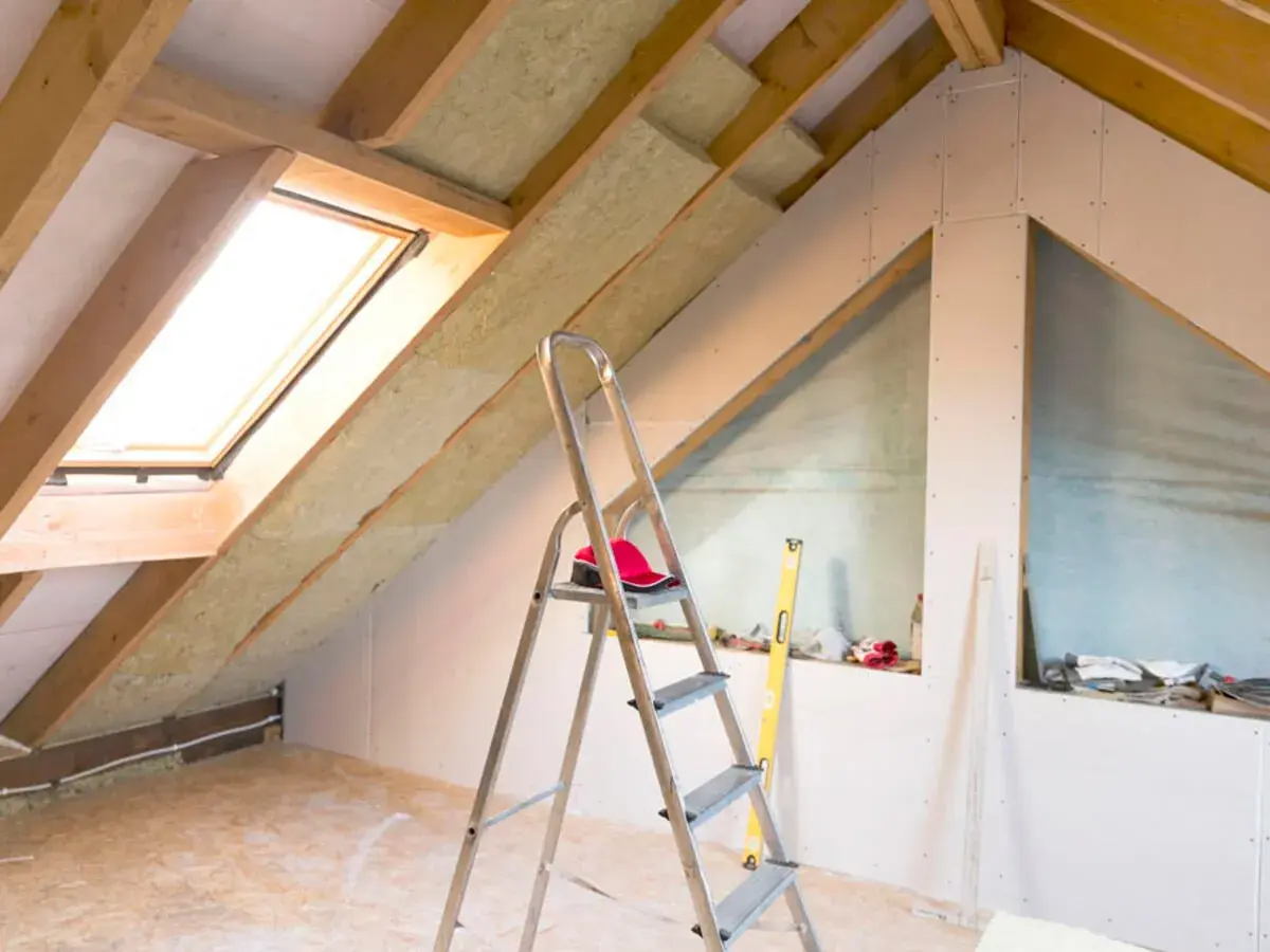 Dachboden ausbauen: Isolierung, Dachfenster und Trockenbauwände schaffen neuen Wohnraum. Werkzeug und Material sind bereit.