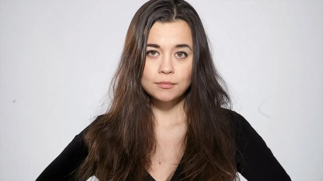 Caroline Ringskog Ferrada-Noli, med sitt långa mörka hår och blick som möter betraktaren, klädd i en svart topp.