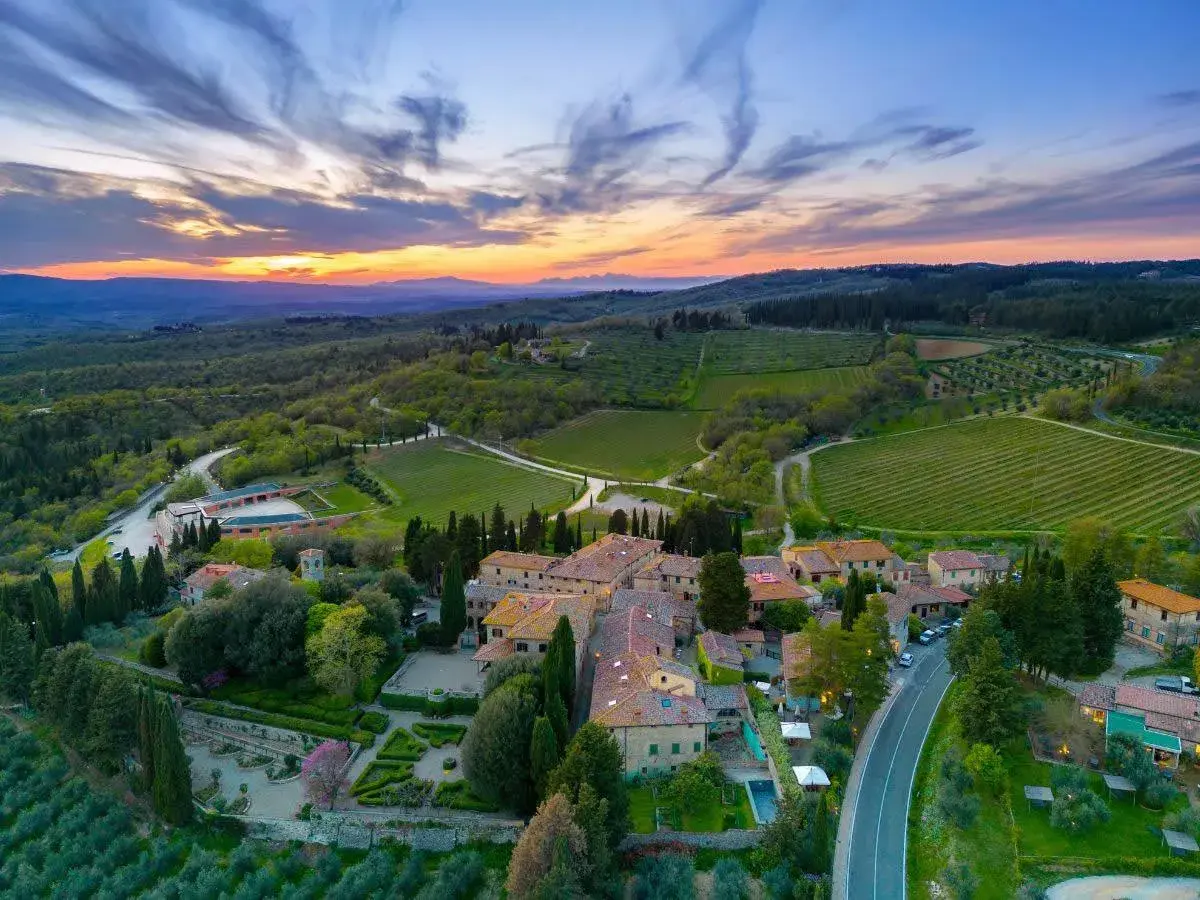 Tramonto mozzafiato sulla **chianti region**, con vigneti rigogliosi e un borgo toscano che si illumina sotto il cielo colorato.