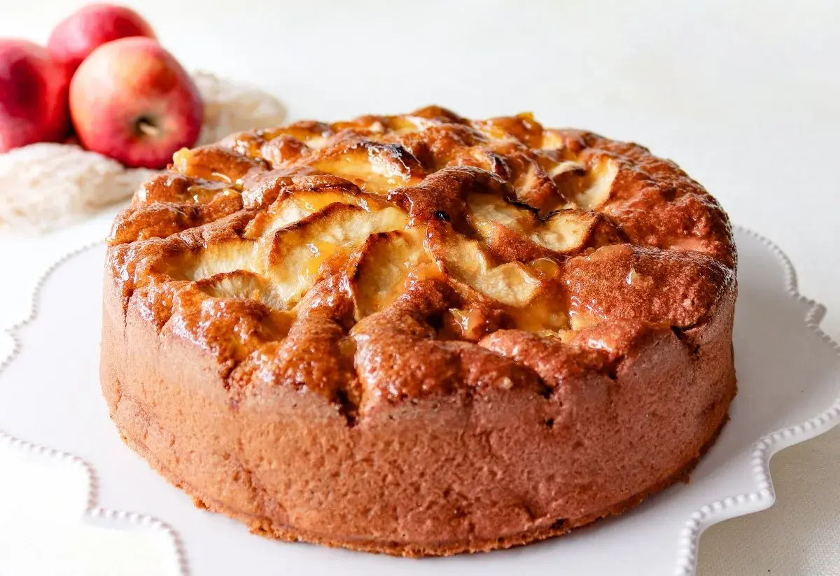 Bizcocho de manzana casero, dorado y jugoso, con trozos de manzana caramelizada en la superficie.