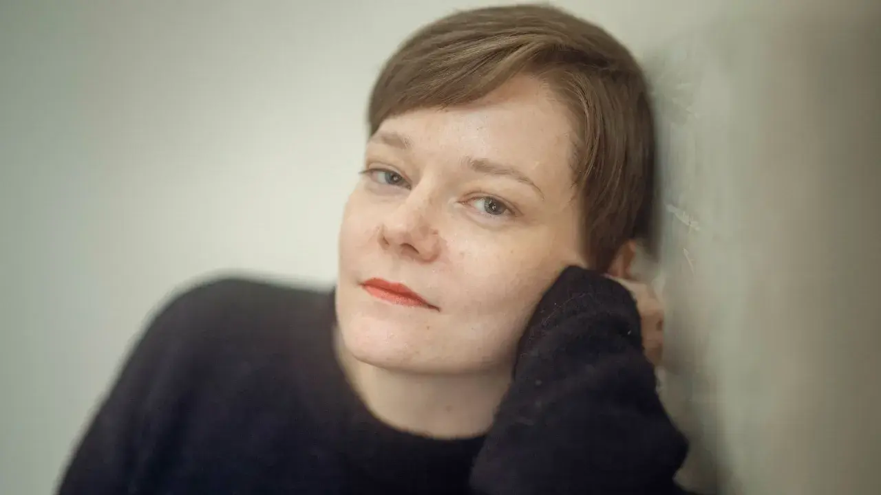 Johanna Frid lutar sig mot en vägg, med handen mot kinden.