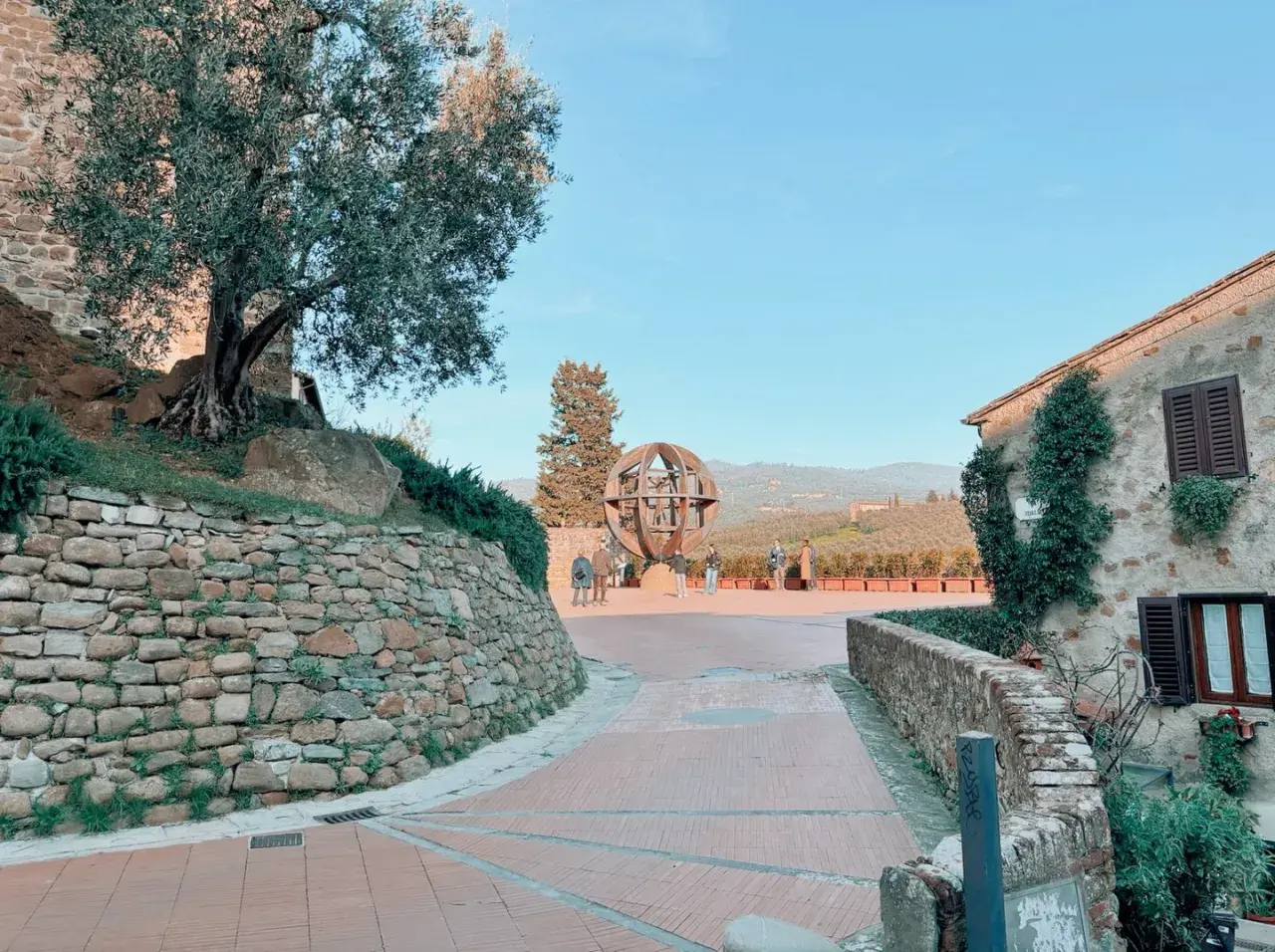 Vinci cosa vedere: un'installazione artistica a forma di globo, un ulivo secolare e case in pietra con vista sulle colline toscane.
