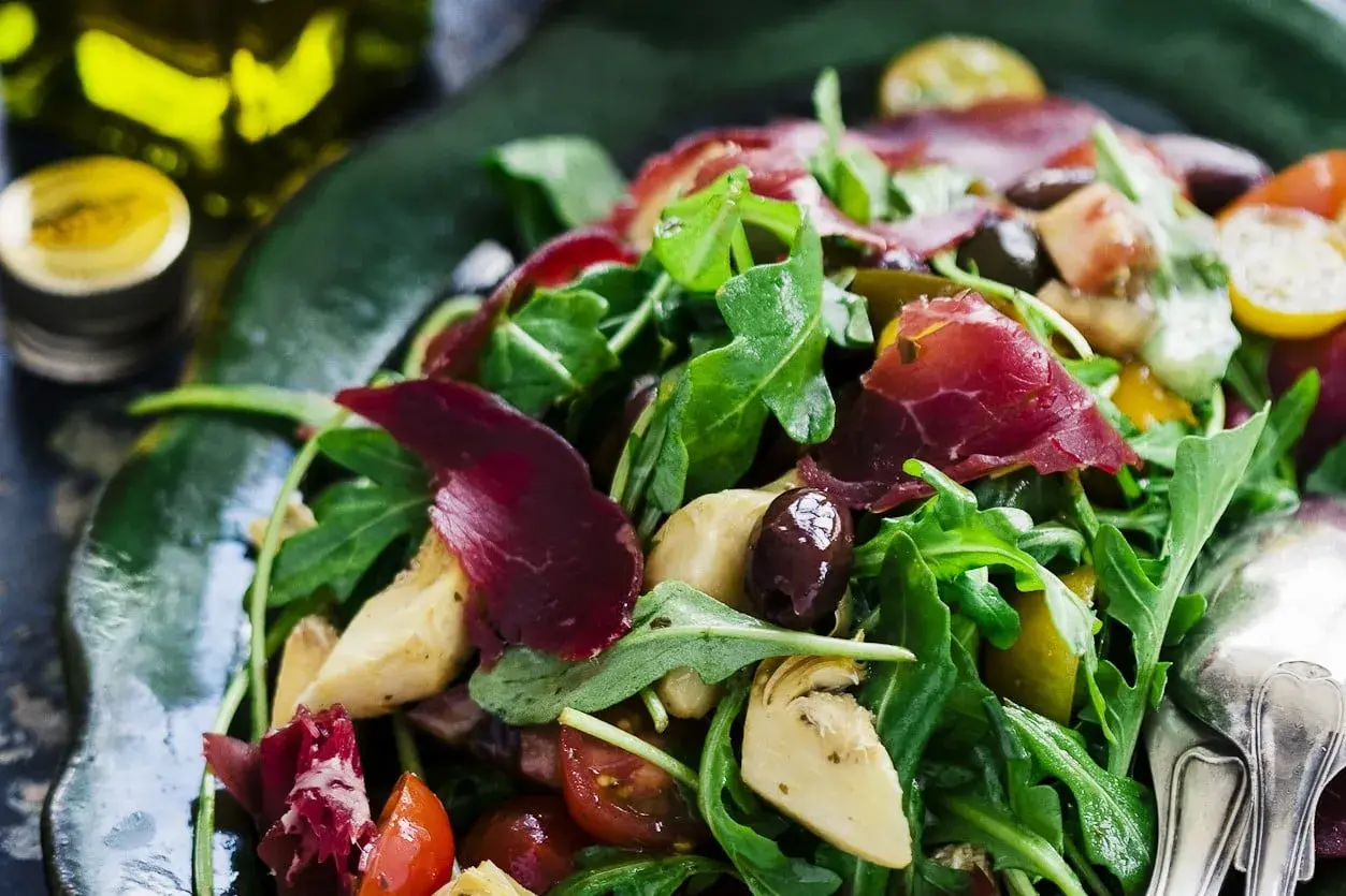 En härlig typisk italiensk sallad med ruccola, lufttorkat kött, oliver, kronärtskocka och tomater.