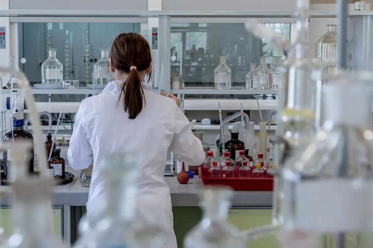 Naukowczyni w białym fartuchu analizuje próbki, badając wskaźnik anizocytozy erytrocytów wśród laboratoryjnego sprzętu.
