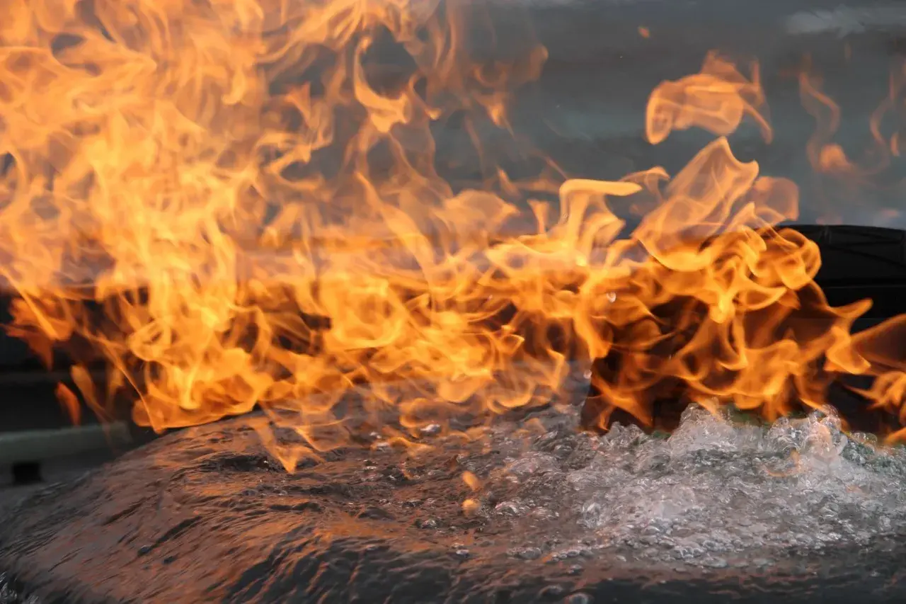 Flammen lodern über sprudelndem Wasser. Das Brandverhalten von CFL-S1-Materialien wird hier eindrucksvoll demonstriert.