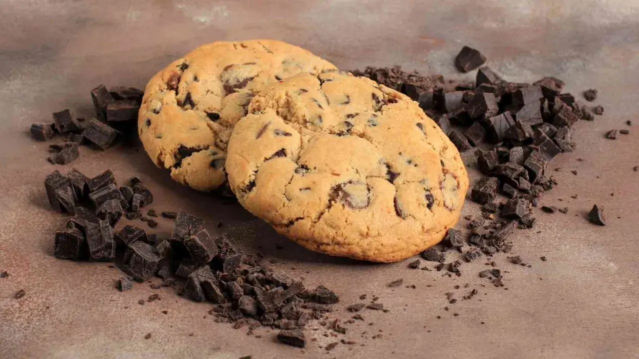 Due golosi crumble cookies con gocce di cioccolato, circondati da pezzetti di cioccolato fondente. La ricetta perfetta per un momento di dolcezza.