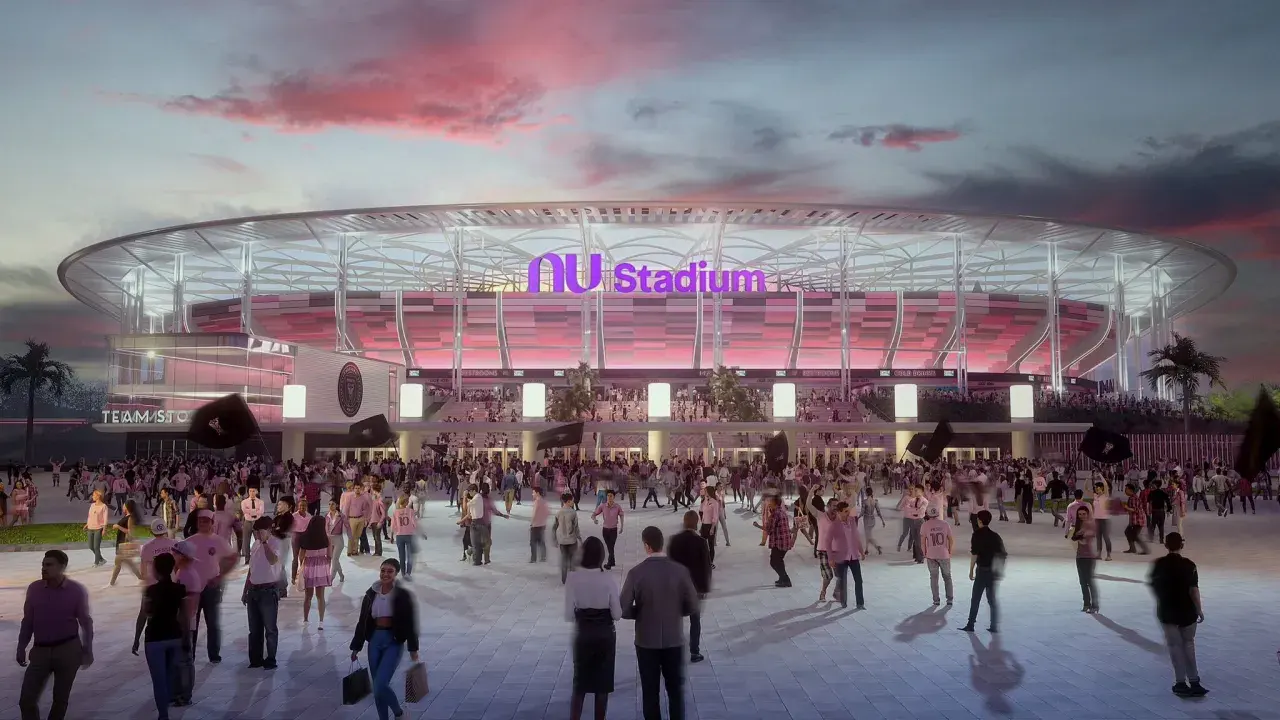 Tłum kibiców zmierza na mecz do Inter Miami Stadium. Zachodzące słońce maluje niebo na różowo, a stadion lśni w różowych barwach.