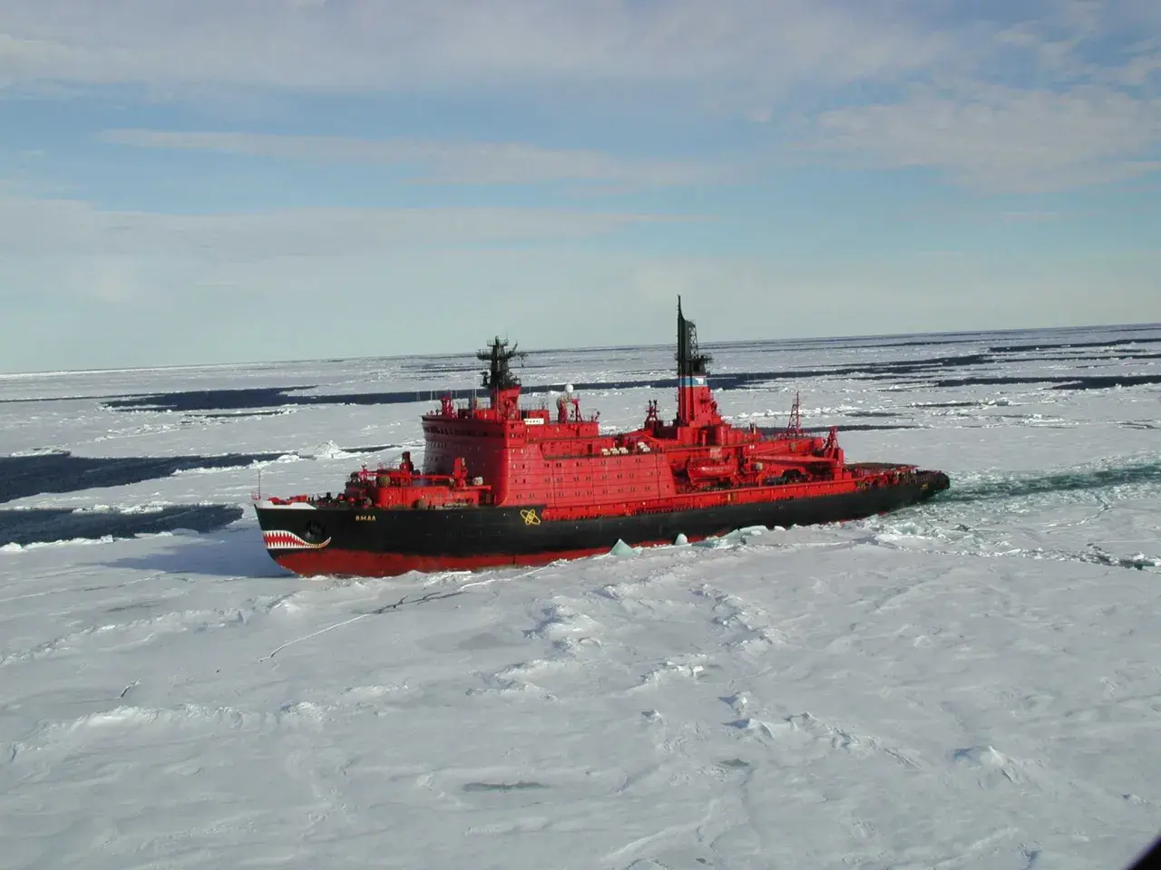 Ein rotes Eisbrecher-Schiff mit Haifischzähnen am Bug kämpft sich durch gefrorenes Wasser.