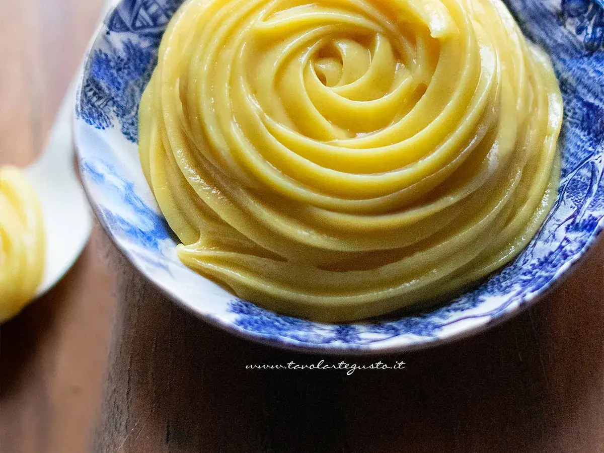 Crema pasticcera senza uova, liscia e vellutata, servita in una ciotola decorata con motivi blu.