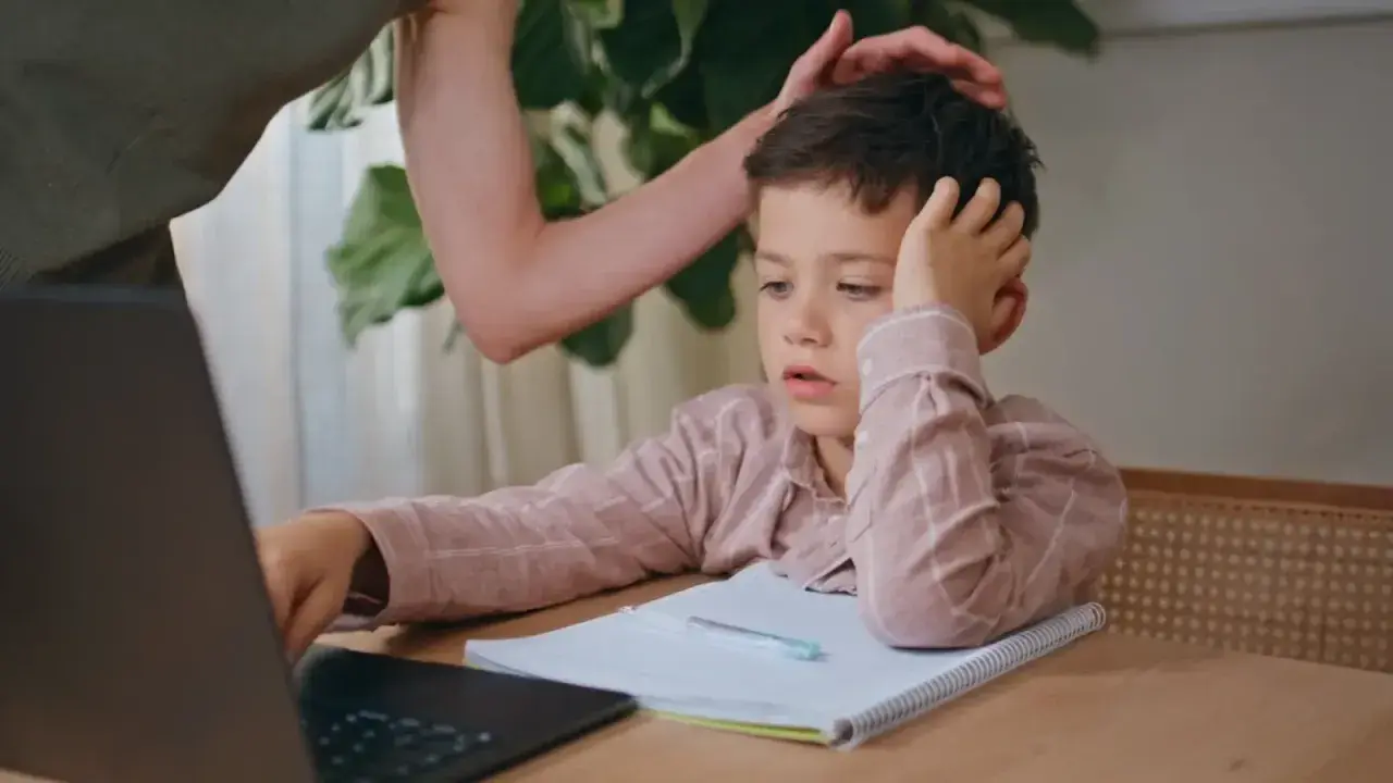 Chłopiec zapatrzony w ekran, z ręką na głowie, wygląda, jakby gdy dziecku na niczym nie zależy. Mama próbuje go zachęcić.