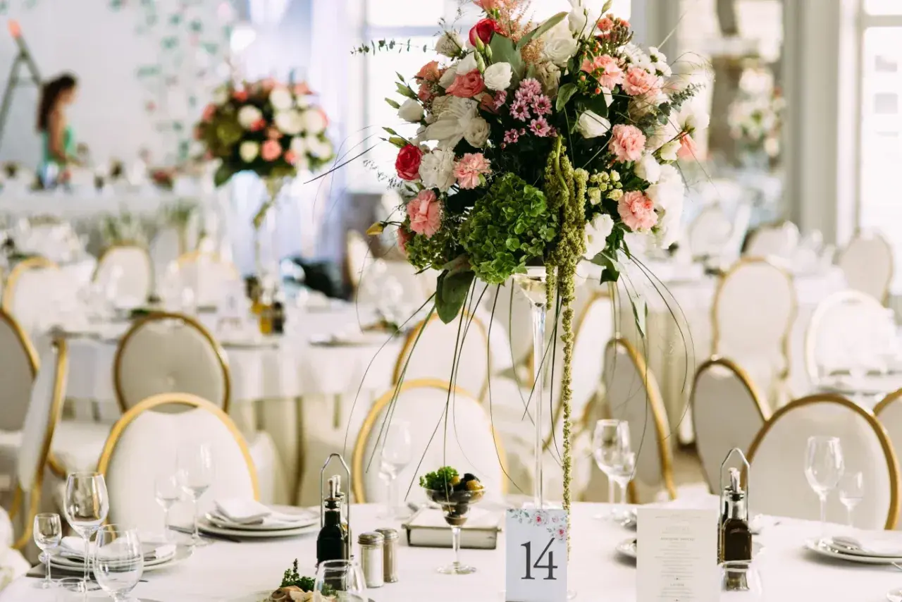 Elegancka dekoracja stołu weselnego z bukietem kwiatów i numerem 14. Sprawdź wedding planner cena, by zorganizować wymarzone przyjęcie.