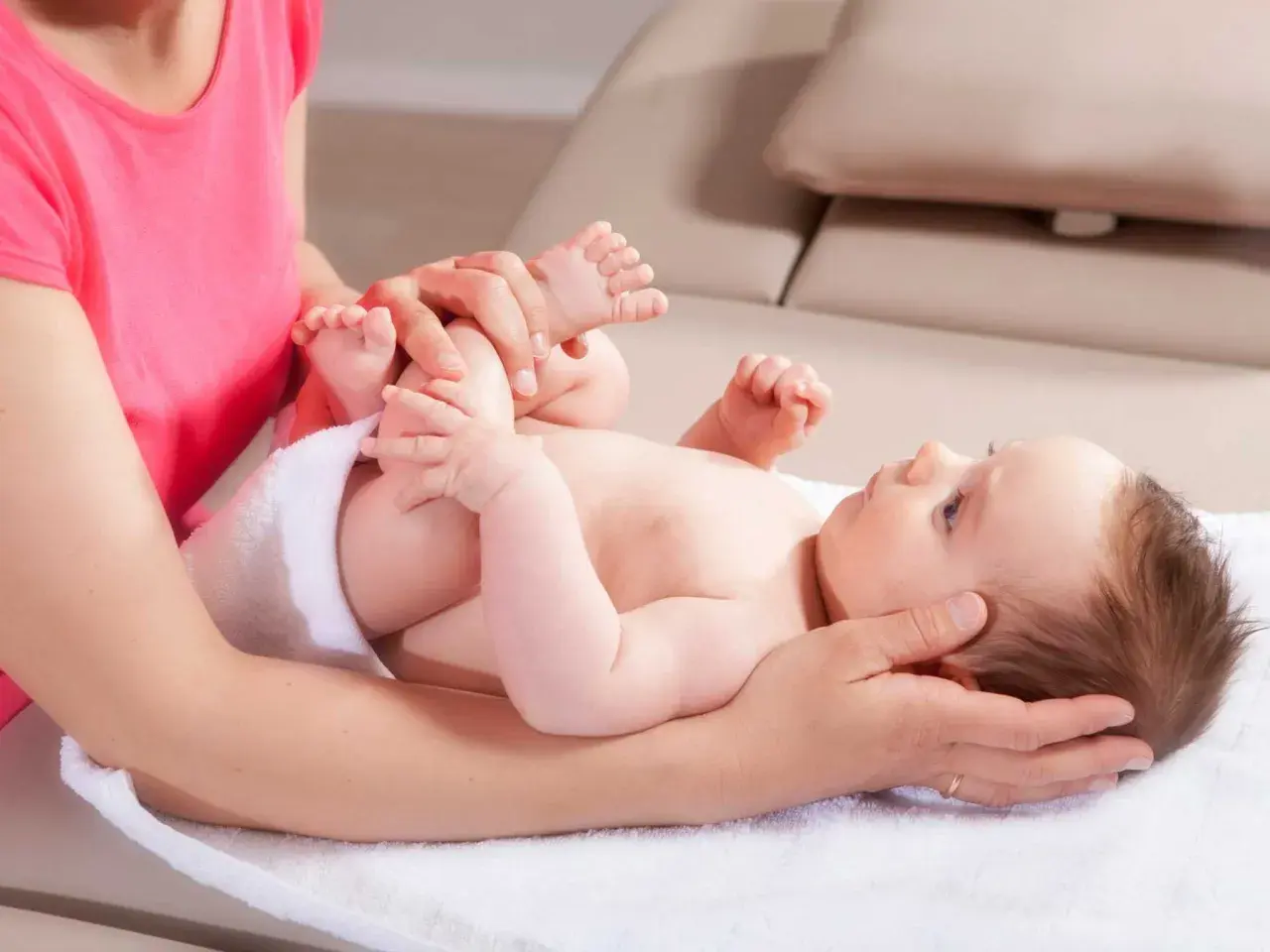 Sanfte Hände untersuchen die Füße eines Babys. Eine Mutter fragt sich, wann mit Baby zum Osteopathen gehen sollte, um solche Behandlungen zu erhalten.