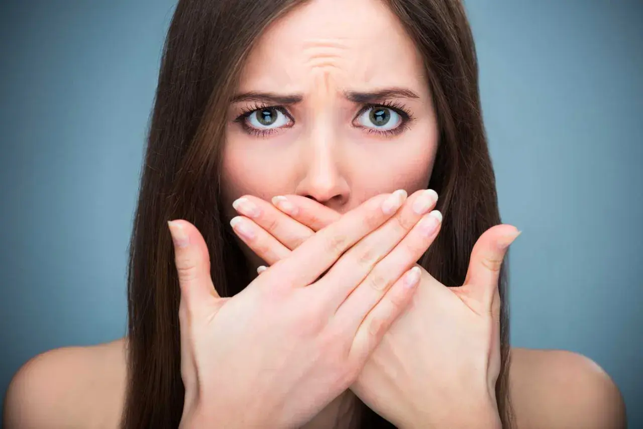 Donna con mani sulla bocca, espressione preoccupata, forse per la salivazione eccessiva.