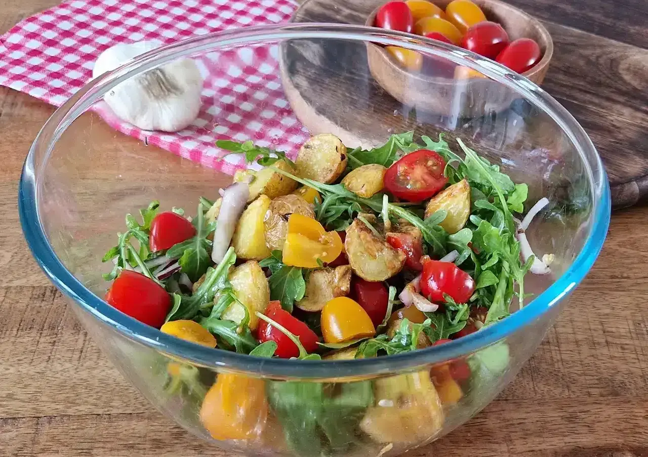 Salade colorée avec pommes de terre rôties, tomates cerises et roquette. Une option légère pour une salade pour maigrir du ventre.