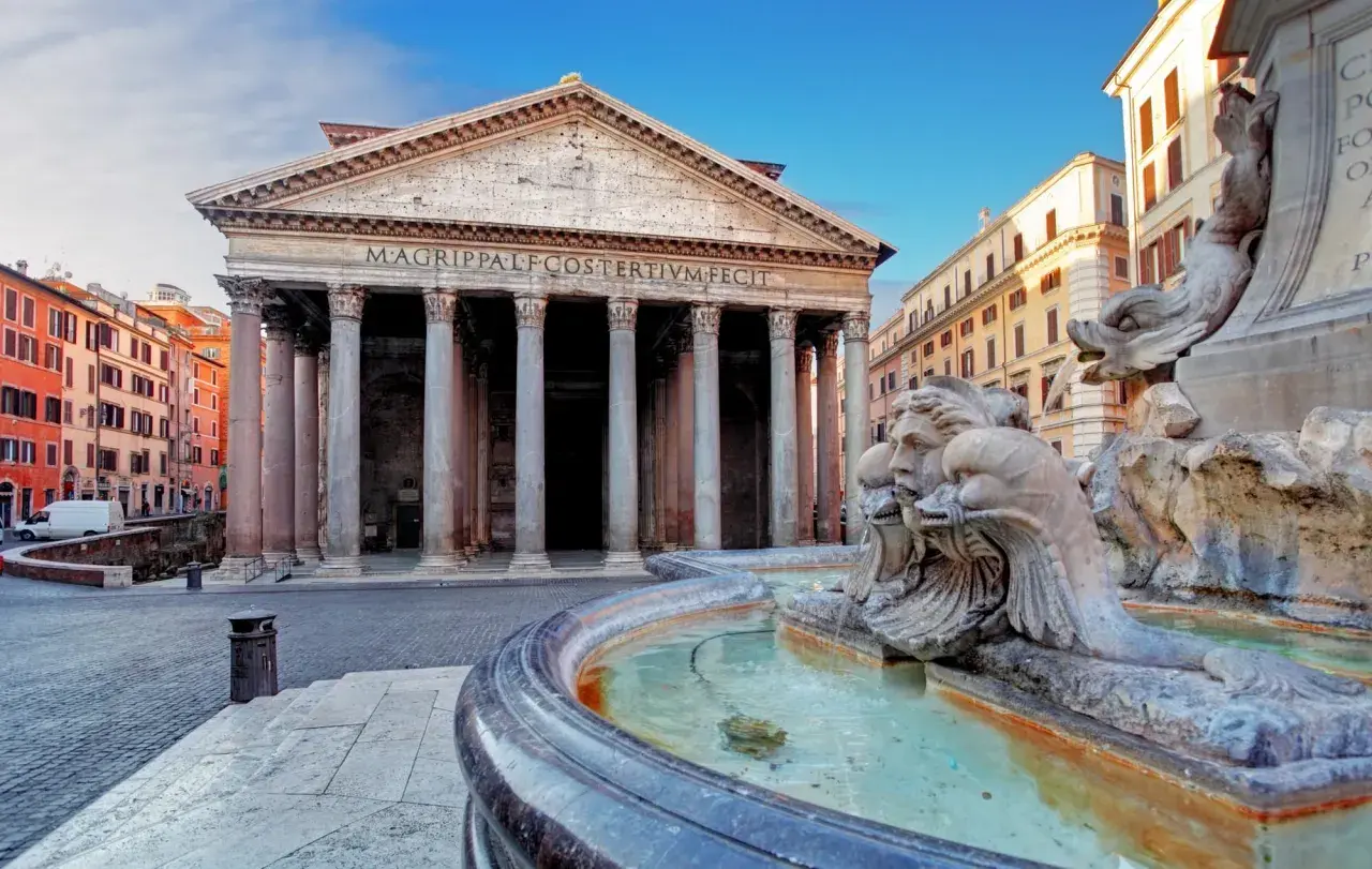 Fontana di Piazza della Rotonda Pantheon, con le sue sculture di delfini e volti, riflette la maestosità dell'edificio antico.