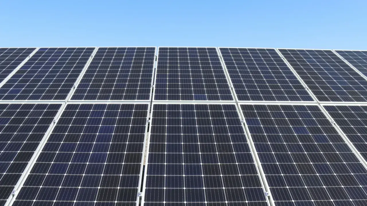 Duża instalacja PV pod błękitnym niebem. Panele słoneczne tworzą równą, ciemną powierzchnię, gotową do produkcji czystej energii.