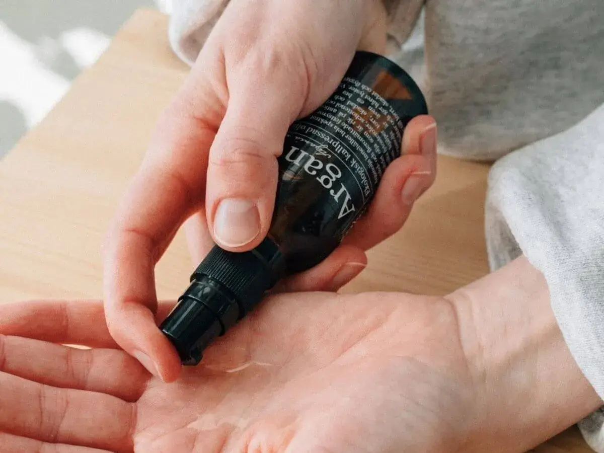 En hand pumpar ut arganolja i en annan handflata. Oljan är ekologisk och kallpressad.