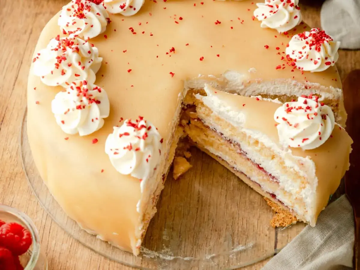 Ein köstliches Marzipantorte Rezept: saftiger Kuchen mit Marzipan, Sahne und Himbeermarmelade, verziert mit Tupfen und roten Streuseln.