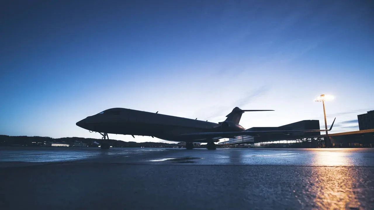 Ein Privatjet steht auf einem nassen Rollfeld bei Dämmerung.