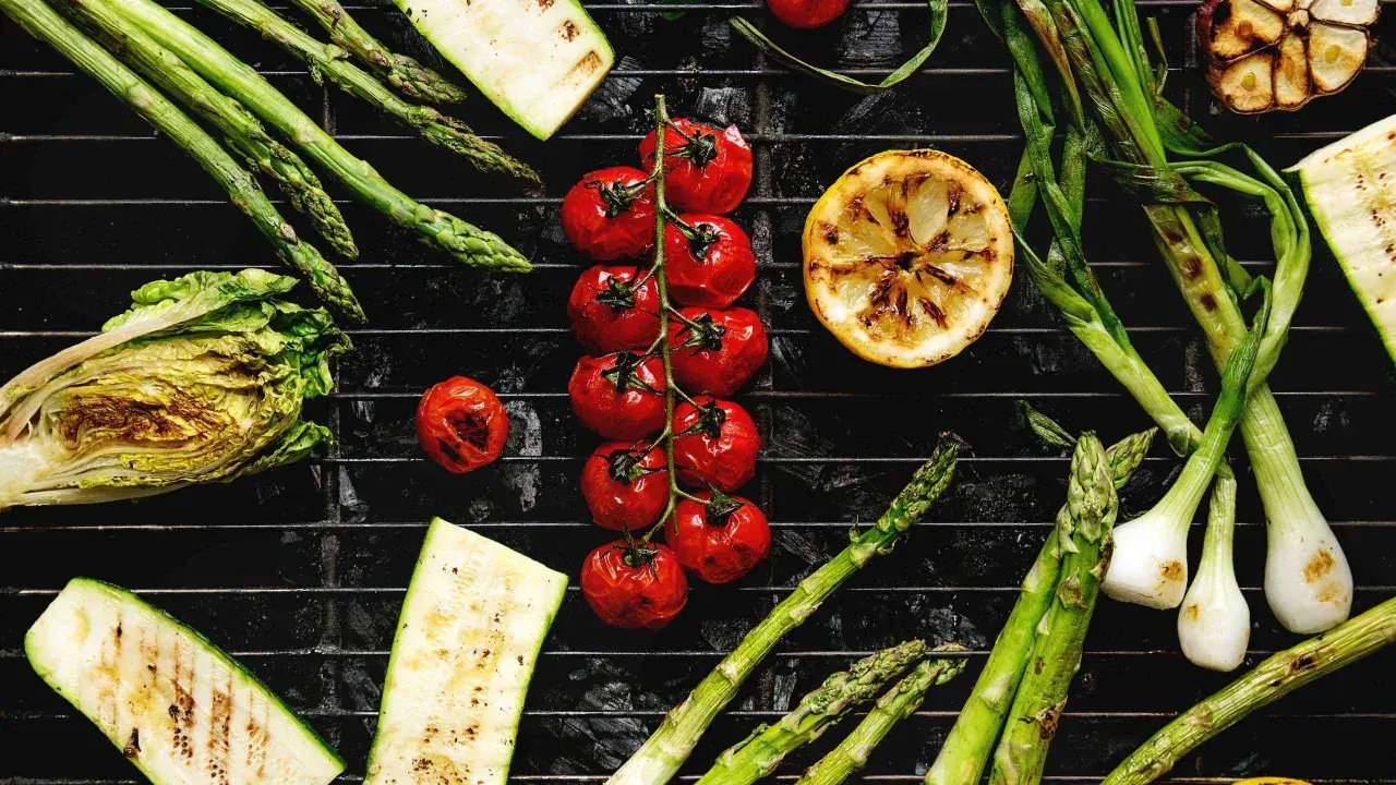 Légumes au barbecue charbon de bois : asperges, tomates cerises, courgettes, oignons nouveaux, citron et chou.