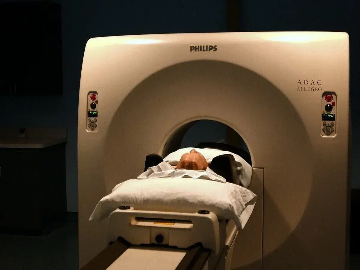 Pacjent leży na łóżku aparatu do tomografii głowy Philips ADAC Allegro.