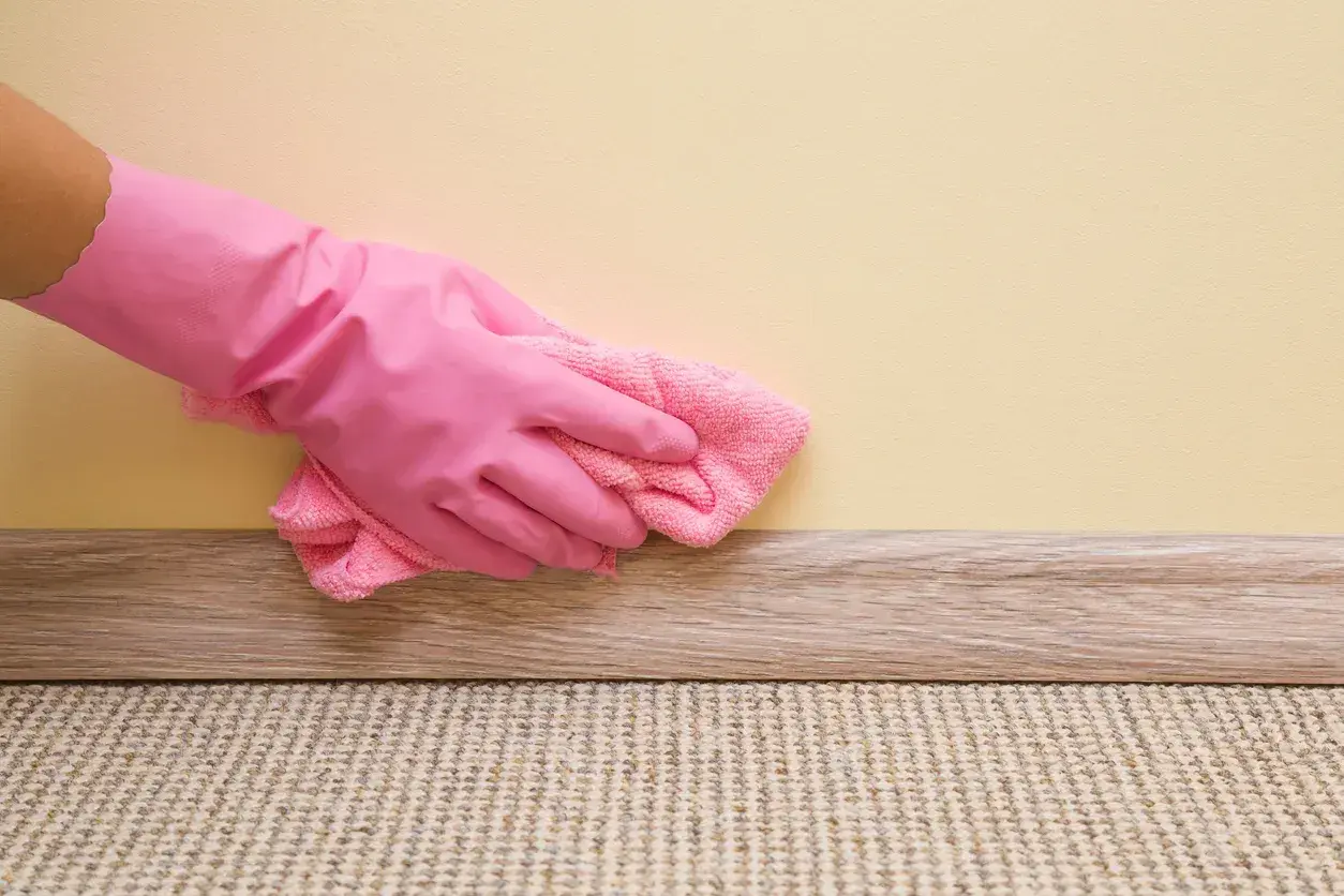 Mano con guanto rosa pulisce la pittura lavabile con un panno rosa.