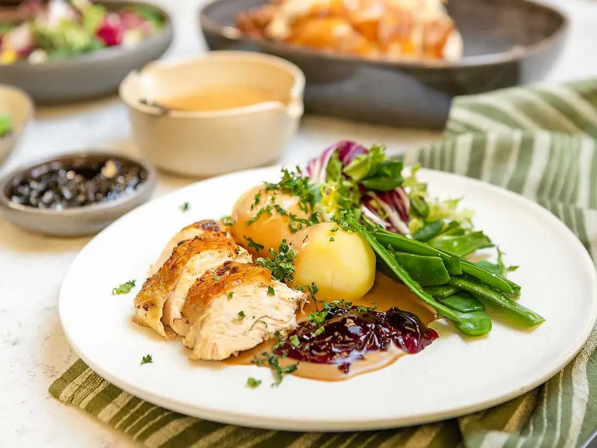 En saftig hel kyckling i ugn, skuren i skivor, serveras med potatis, gröna bönor och en härlig sås.
