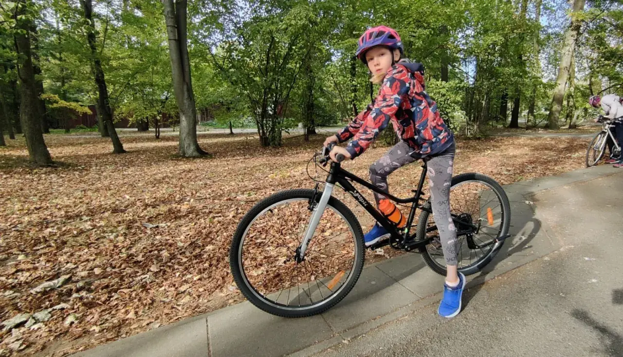 Dziewczynka na rowerze, idealny rower dla 10 latka ile cali? W parku jesienią.