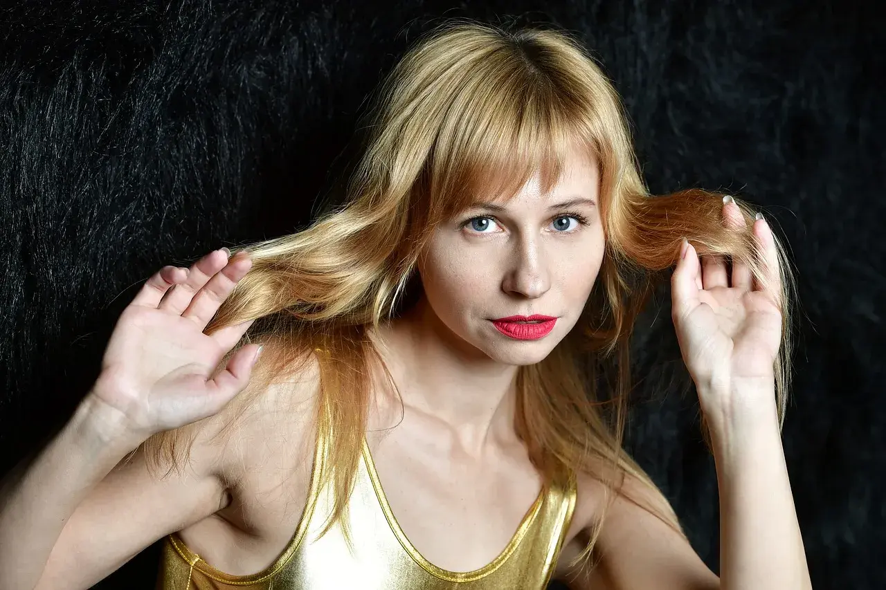 Kobieta z blond grzywką i niebieskimi oczami, zastanawiająca się, ile rośnie grzywka w tydzień.