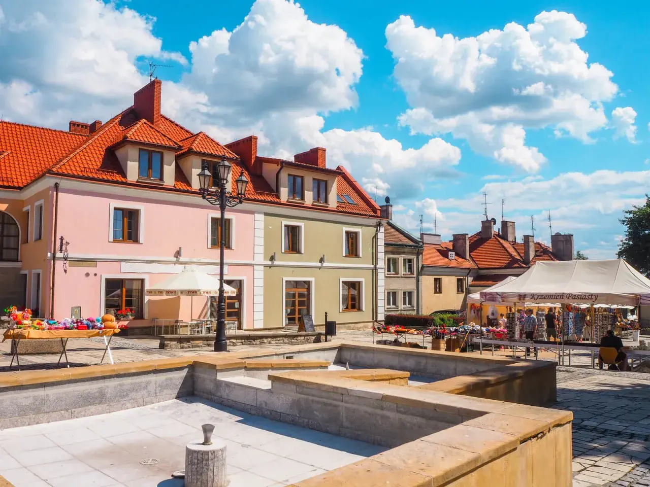 Sandomierz rynek tętni życiem. Kolorowe kamienice, stragany z pamiątkami i błękitne niebo tworzą malowniczy widok.