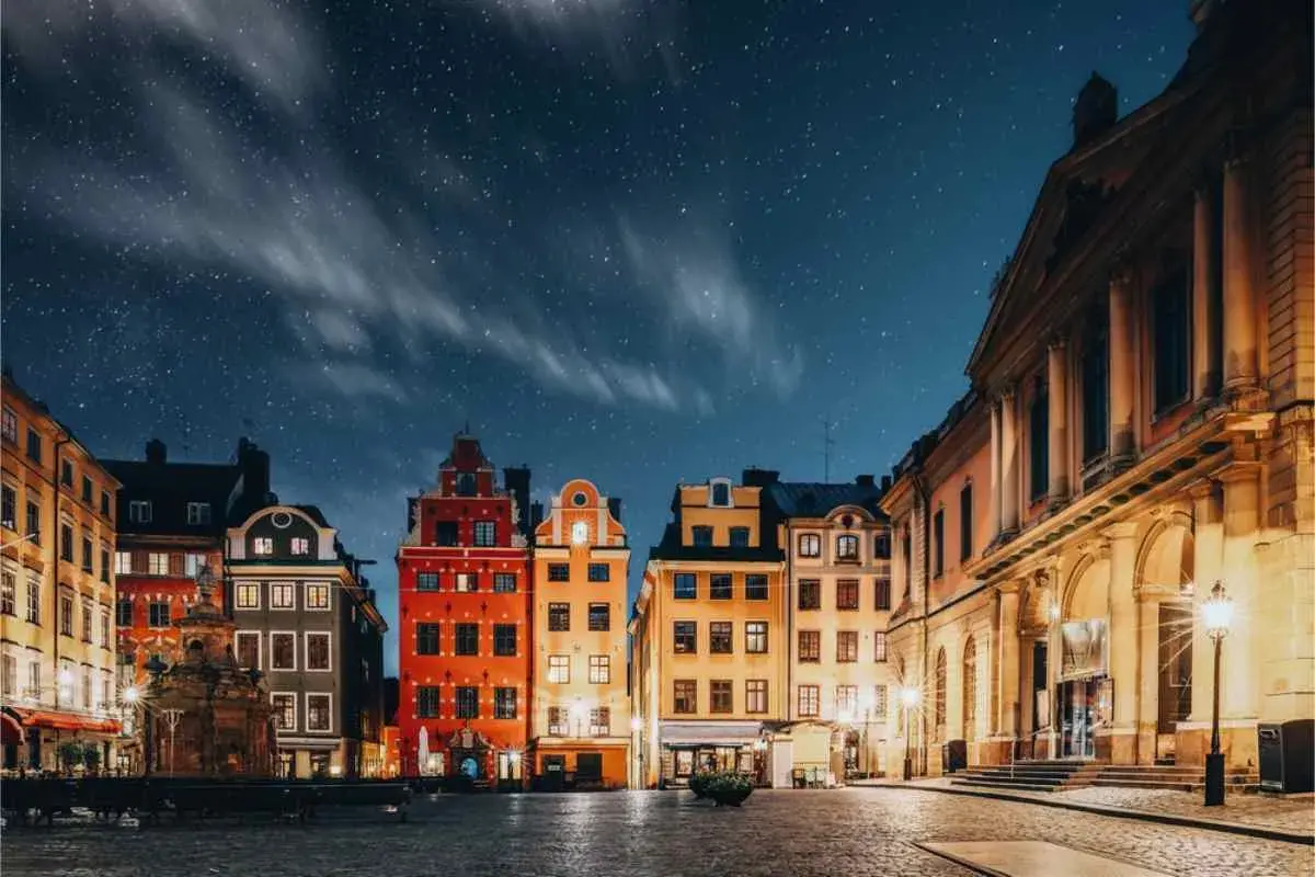 Stokholm stare miasto under en stjärnklar natt. Färgglada hus och kullerstensgator lyser upp torget.