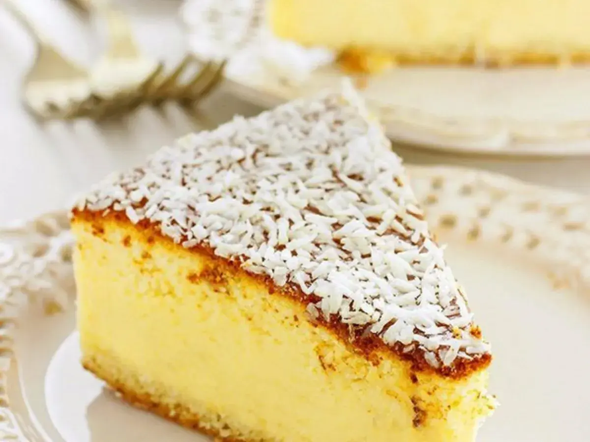 Una fetta di torta alla ricotta veloce e morbidissima, cosparsa di cocco grattugiato, su un piatto bianco.