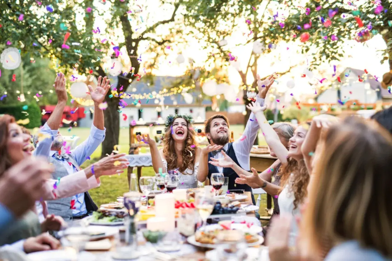 Fröhliche Gäste werfen Konfetti bei einer Gartenparty. Tolle **Gartenparty Ideen** für unvergessliche Momente mit Freunden und Familie.